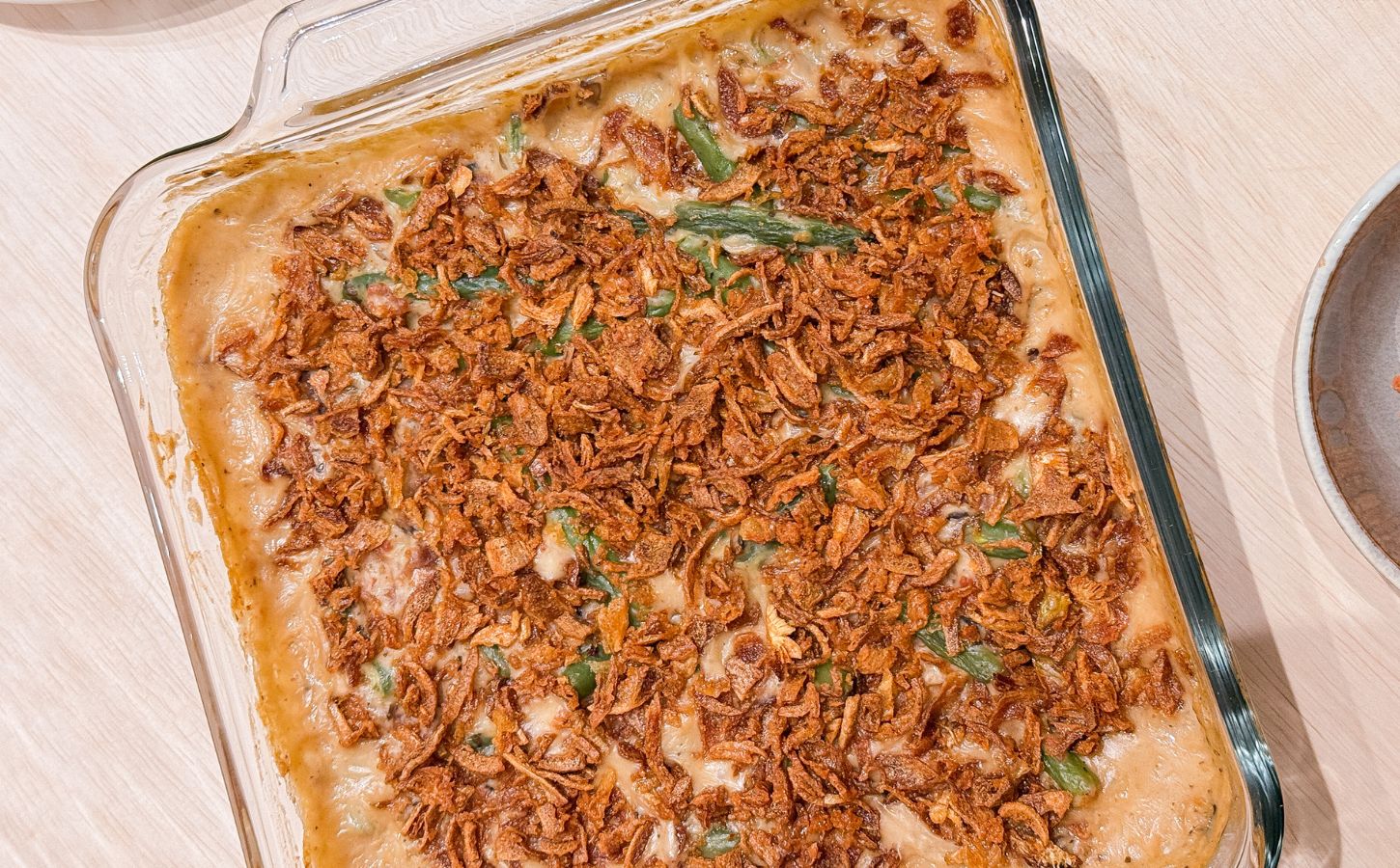 a dish of vegan parmesan bacon green bean casserole with mushroom soup and French-fried onions