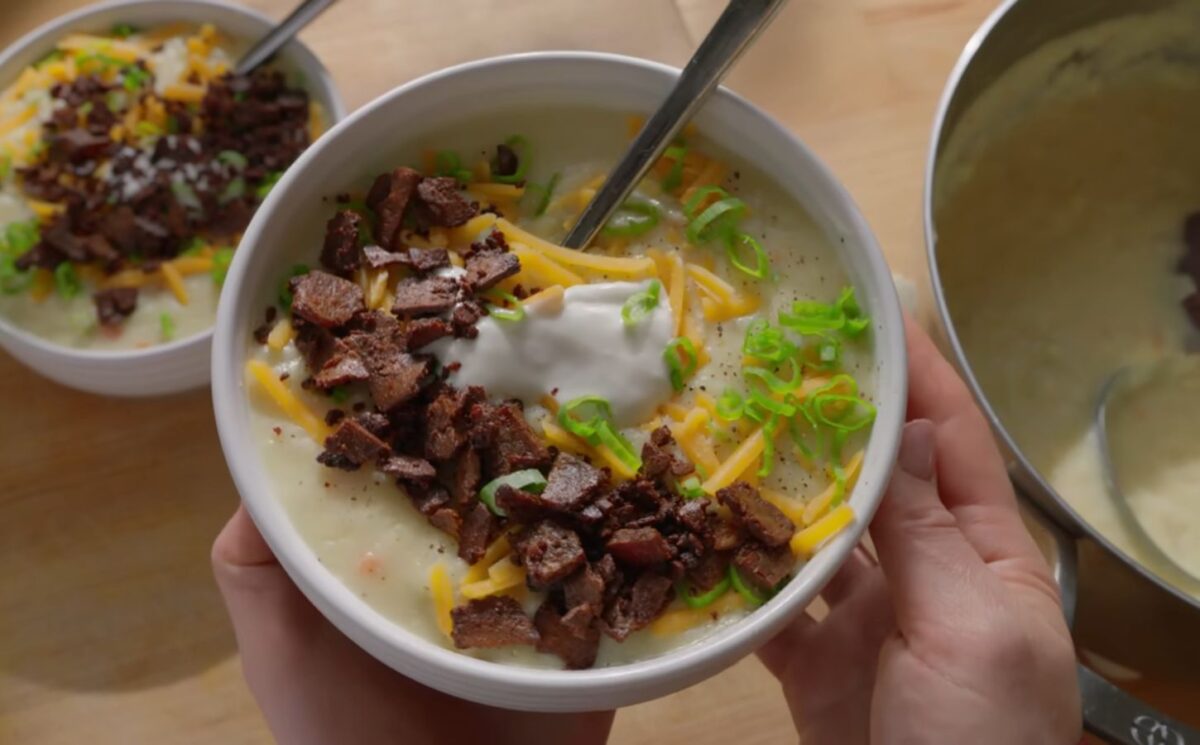 A bowl of loaded baked potato soup topped with smoky tofu bacon, vegan cheese, and scallions, one of Sarah Sullivan’s cozy vegan winter soups