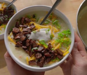 A bowl of loaded baked potato soup topped with smoky tofu bacon, vegan cheese, and scallions, one of Sarah Sullivan’s cozy vegan winter soups