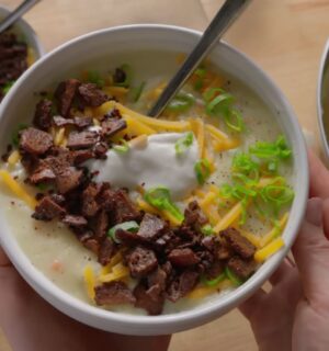 A bowl of loaded baked potato soup topped with smoky tofu bacon, vegan cheese, and scallions, one of Sarah Sullivan’s cozy vegan winter soups