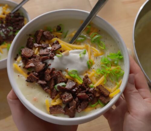 A bowl of loaded baked potato soup topped with smoky tofu bacon, vegan cheese, and scallions, one of Sarah Sullivan’s cozy vegan winter soups