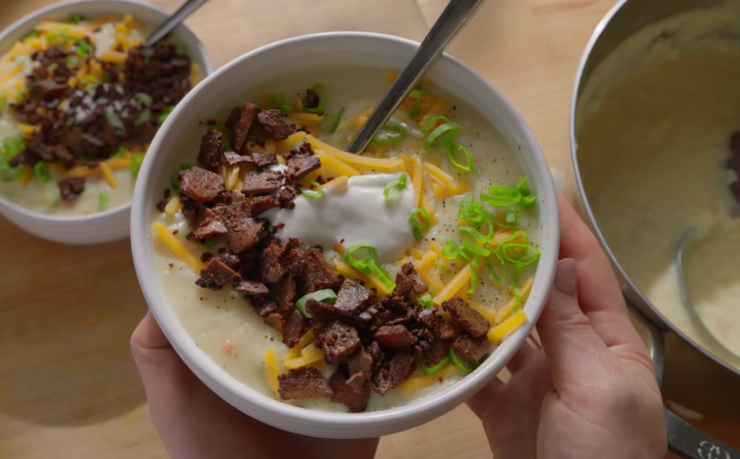 A bowl of loaded baked potato soup topped with smoky tofu bacon, vegan cheese, and scallions, one of Sarah Sullivan’s cozy vegan winter soups