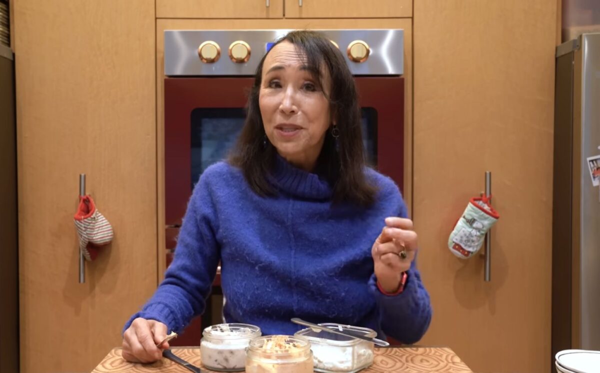 Miyoko Schinner stands behind the 3 varieties of her cashew cream cheese in her kitchen