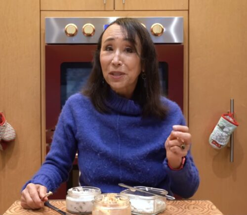 Miyoko Schinner stands behind the 3 varieties of her cashew cream cheese in her kitchen