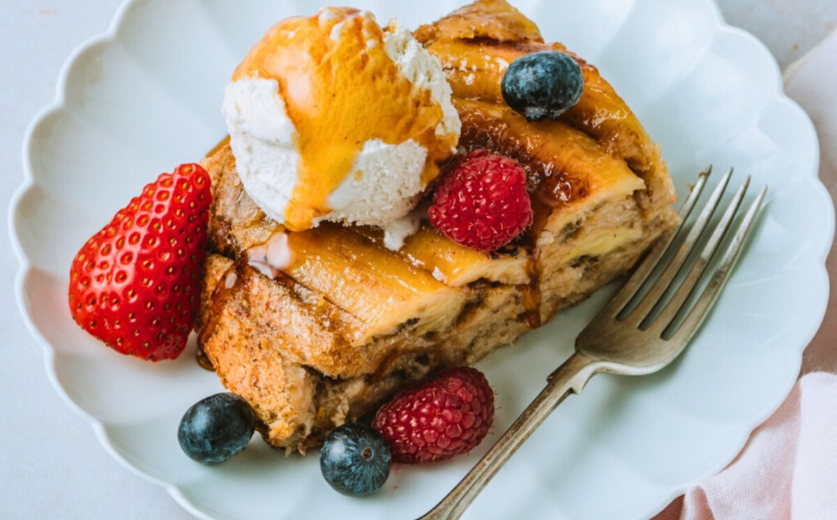 a picture of a slice of banana Tarte Tatin French toast topped with vegan ice cream, maple syrup and berries for cozy vegan breakfasts