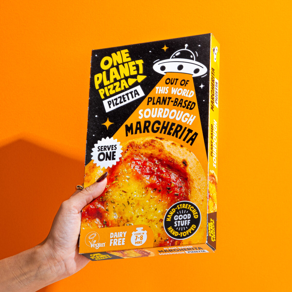 Photo shows a hand holding up the One Planet Pizza Margherita "Pizzetta," a single-serve frozen pizza that is available at Aldi for the month