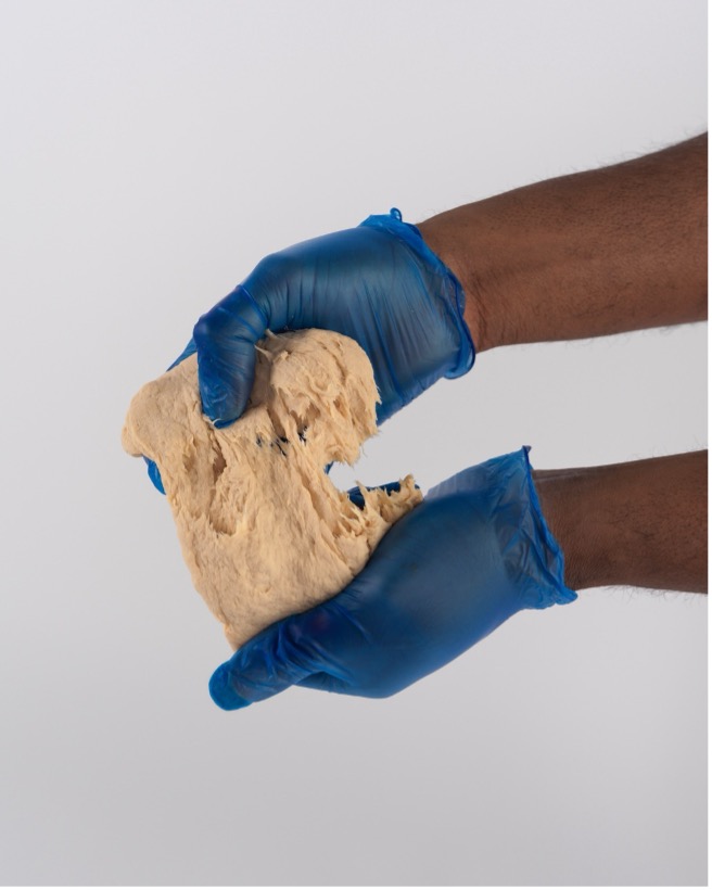 Photo shows someone wearing blue gloves and holding up a large piece of mycoprotein