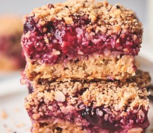 stacked breakfast berry chia bard with banana, maple syrup, rolled oats, frozen berries, and a crumble topping