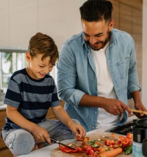 Photo shows a man and his son preparing and cooking vegetables in a kitchen. According to a new survey, the majority of Canadians would like to eat more plant-based foods.