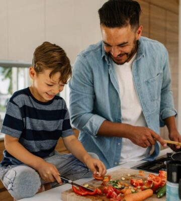 Photo shows a man and his son preparing and cooking vegetables in a kitchen. According to a new survey, the majority of Canadians would like to eat more plant-based foods.