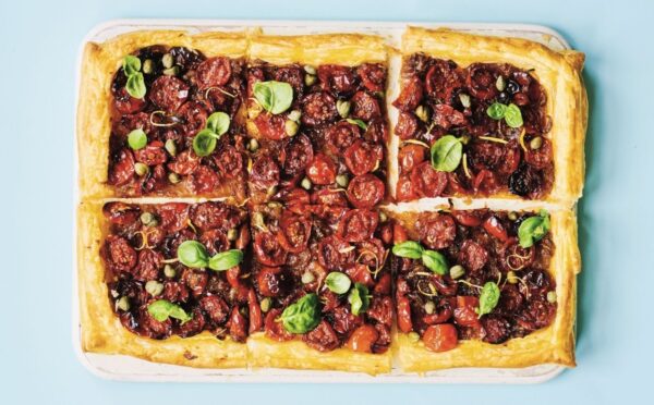 a picture of six squares of a caramelized shallot and tomato tart topped with basil and capers for vegan savory tart ideas for both sweet and savory recipes
