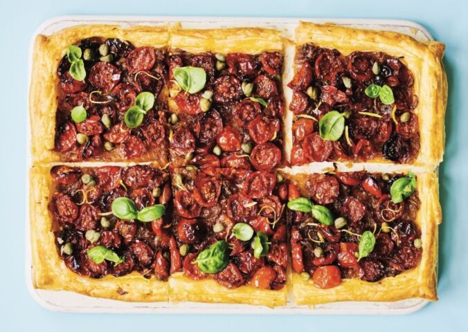 a picture of six squares of a caramelized shallot and tomato tart topped with basil and capers for vegan savory tart ideas for both sweet and savory recipes