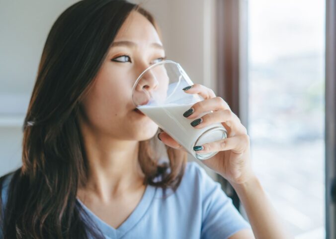 Photo shows a young woman drinking milk while looking out of her kitchen window. New research by Danone and INNOFACT has found that nearly half of German adults now drink plant-based milk alternatives