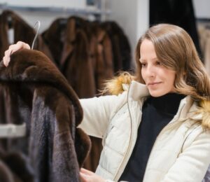 Photo shows a woman holding up a fur coat in a store that sells a lot of fur-related fashion. According to PETA UK, here's how to tell the difference between faux fur and the real thing.