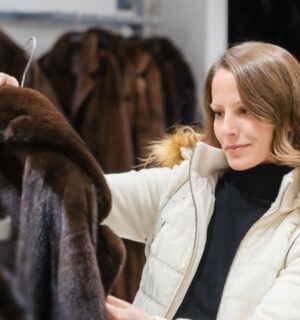Photo shows a woman holding up a fur coat in a store that sells a lot of fur-related fashion. According to PETA UK, here's how to tell the difference between faux fur and the real thing.