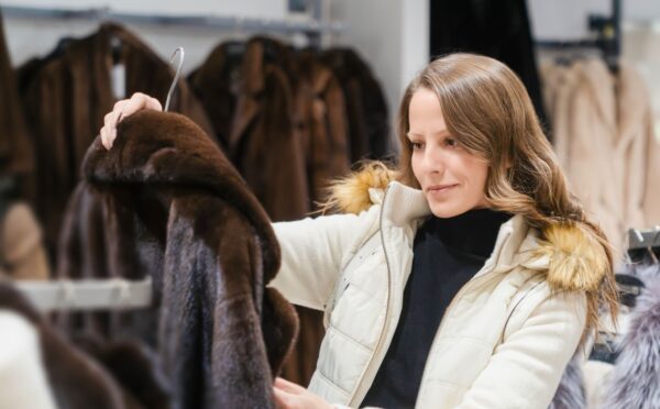 Photo shows a woman holding up a fur coat in a store that sells a lot of fur-related fashion. According to PETA UK, here's how to tell the difference between faux fur and the real thing.