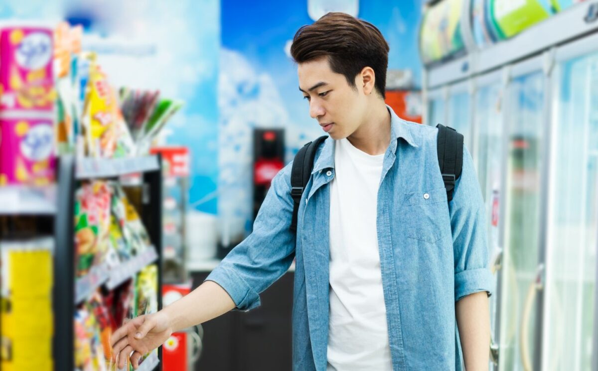 Photo shows a young man about to pick up a food production from a supermarket shelf. A new study’s “promising results” indicate that emphasizing protein on plant-based food labels is the most effective way of improving consumer uptake