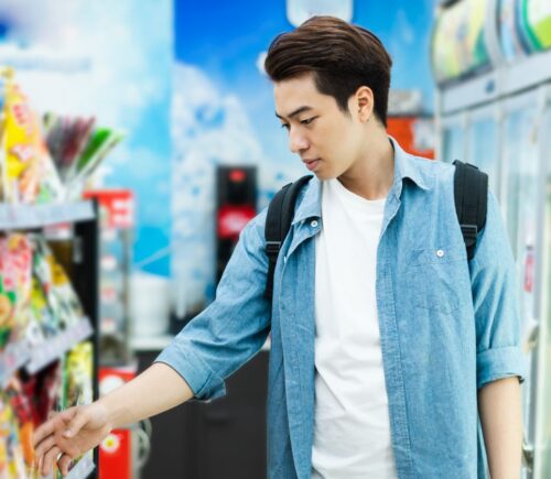 Photo shows a young man about to pick up a food production from a supermarket shelf. A new study’s “promising results” indicate that emphasizing protein on plant-based food labels is the most effective way of improving consumer uptake