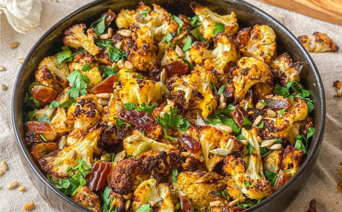 a picture of a bowl of roasted cauliflower salad with dates and tahini served with sunflower seeds for both sweet and savory recipe