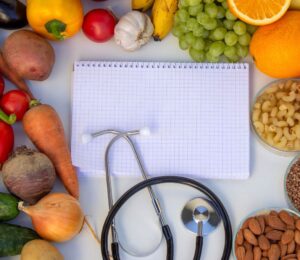 Photo shows a notepad and stethoscope surrounded by fruit, vegetables, nuts, and seeds. A Dr has summarized the top scientific studies of 2025 that support a plant-based diet for health