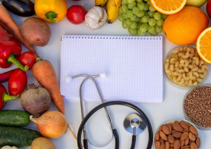 Photo shows a notepad and stethoscope surrounded by fruit, vegetables, nuts, and seeds. A Dr has summarized the top scientific studies of 2025 that support a plant-based diet for health