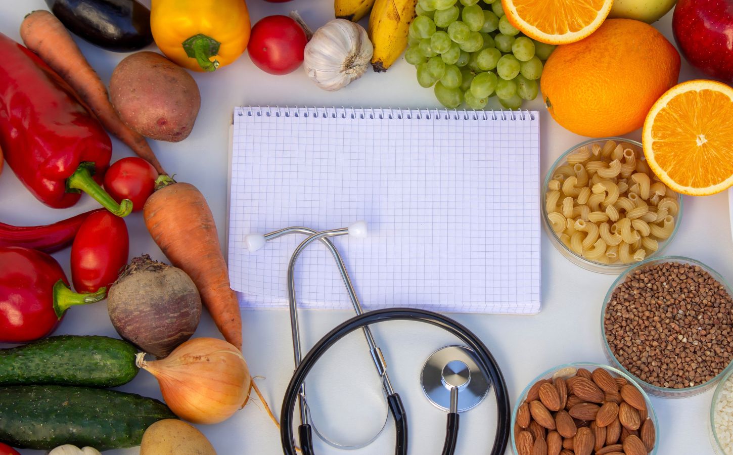 Photo shows a notepad and stethoscope surrounded by fruit, vegetables, nuts, and seeds. A Dr has summarized the top scientific studies of 2025 that support a plant-based diet for health