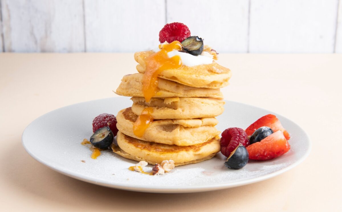a stack of sweet potato pancakes with maple syrup and fruit