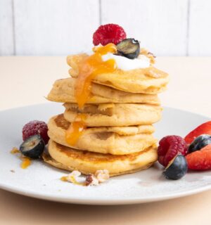 a stack of sweet potato pancakes with maple syrup and fruit