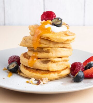 a stack of sweet potato pancakes with maple syrup and fruit