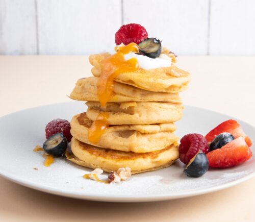 a stack of sweet potato pancakes with maple syrup and fruit