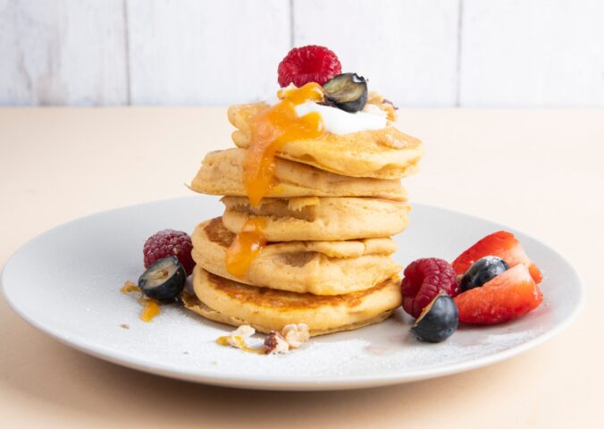 a stack of sweet potato pancakes with maple syrup and fruit