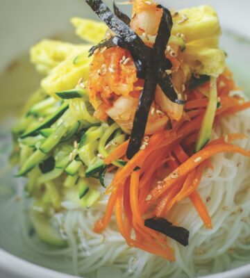 veggie noodles or janchi guksu with thin wheat noodles, radish, soy sauce, sliced onion, and zucchini