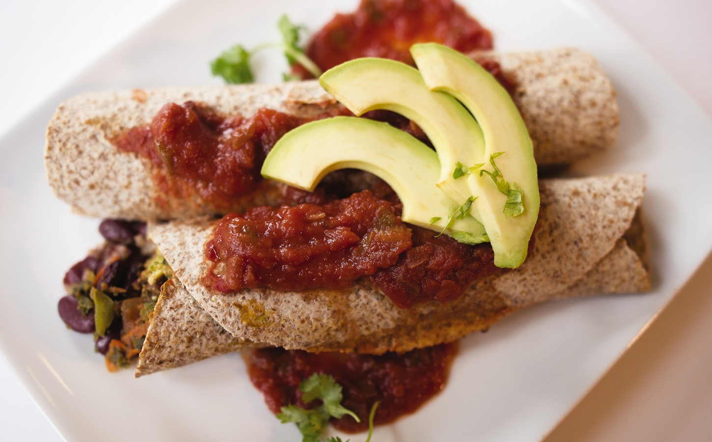 very veggie burritos or enchiladas with pepper, kale, beans, salsa, and avocado