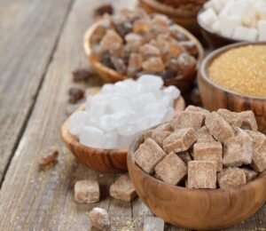 Different types of sugars in wooden bowls to illustrate article about the healthiest vegan sweeteners