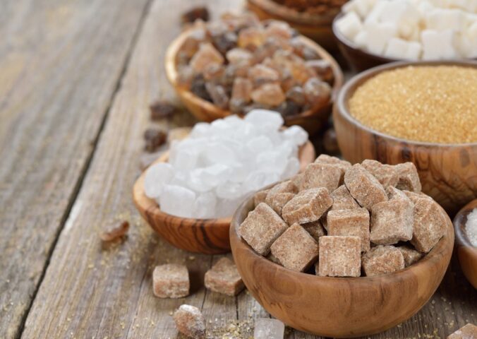 Different types of sugars in wooden bowls to illustrate article about the healthiest vegan sweeteners