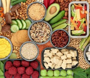 A spread of vegan fresh whole foods including vegetables, legumes, and tofu, illustrating a plant-based diet for skin health