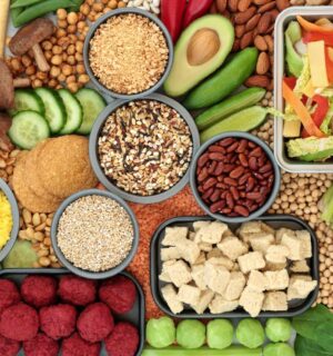 A spread of vegan fresh whole foods including vegetables, legumes, and tofu, illustrating a plant-based diet for skin health