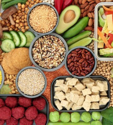 A spread of vegan fresh whole foods including vegetables, legumes, and tofu, illustrating a plant-based diet for skin health