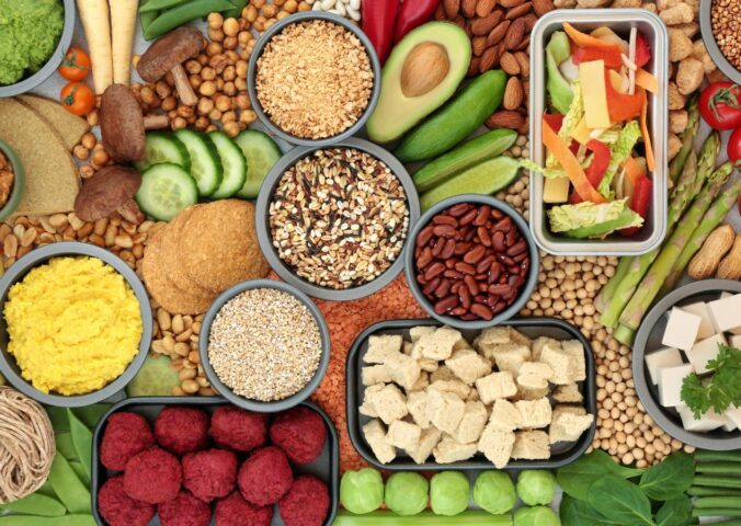 A spread of vegan fresh whole foods including vegetables, legumes, and tofu, illustrating a plant-based diet for skin health