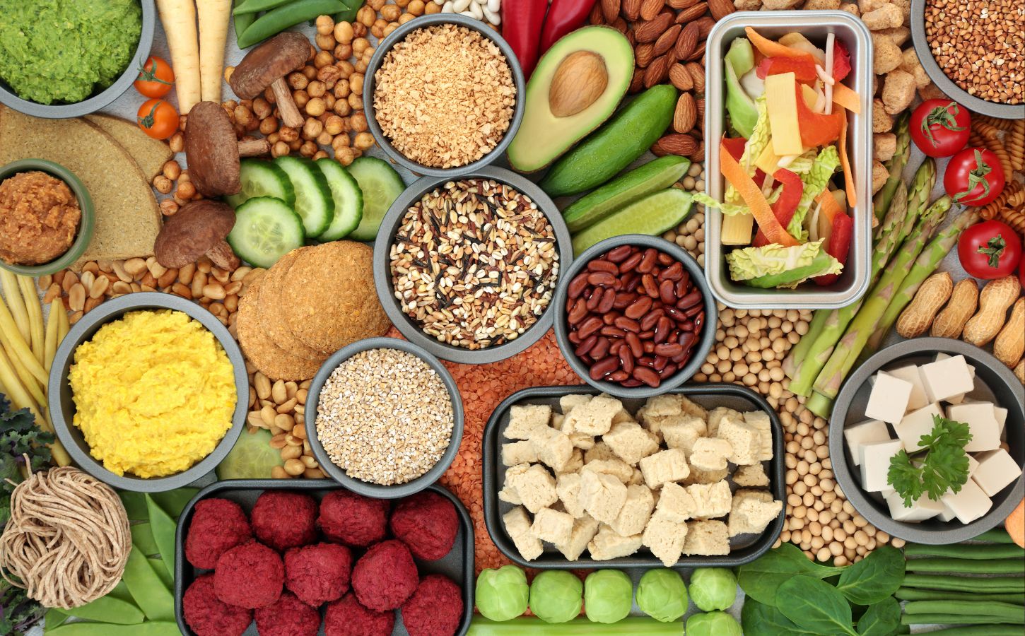 A spread of vegan fresh whole foods including vegetables, legumes, and tofu, illustrating a plant-based diet for skin health