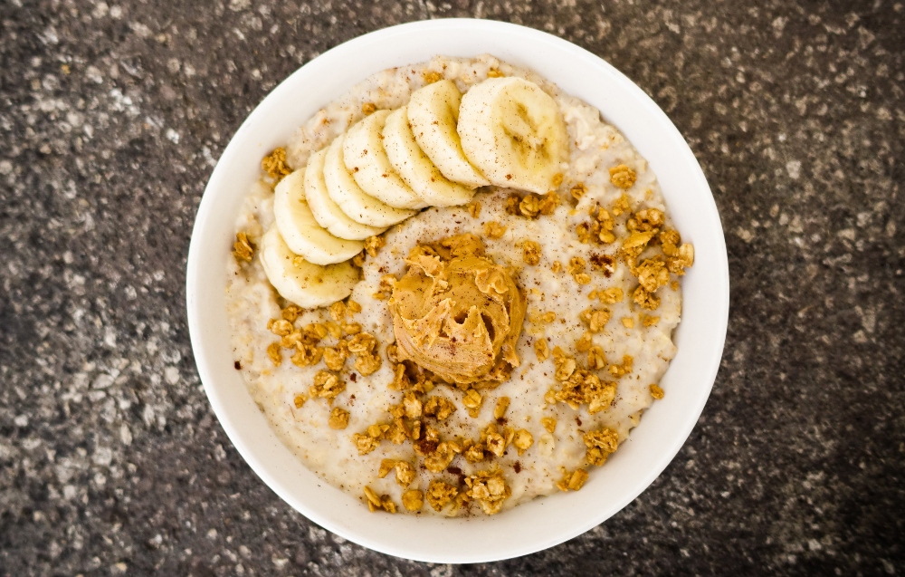 Healthy oatmeal bowl with banana slices, peanut butter and granola to illustrate article about higher NAD+ levels in vegans
