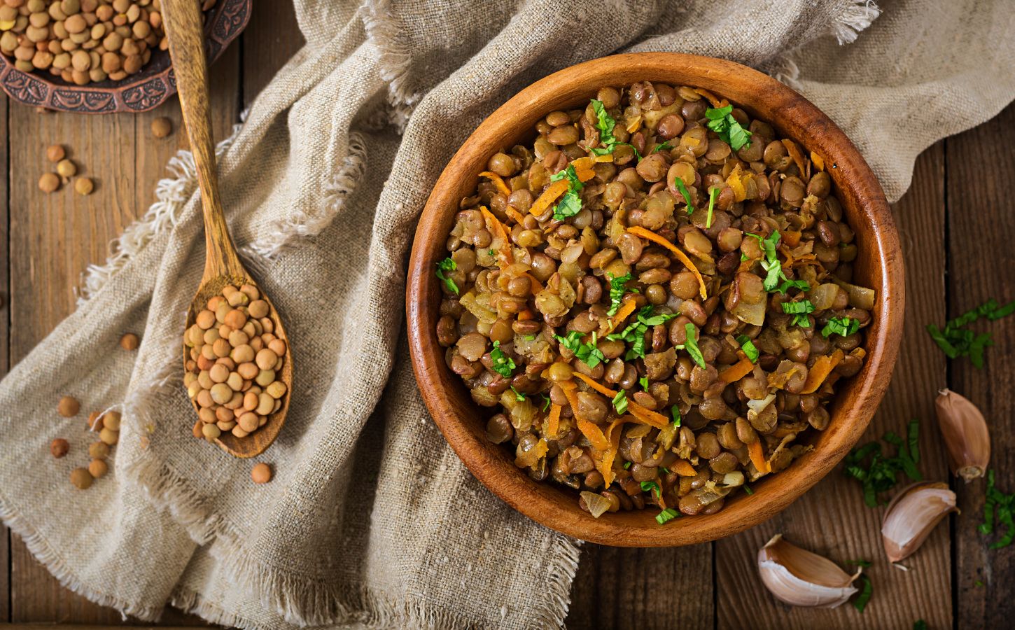 Cooked green lentils with carrot and onion in wooden bowl to illustrate article about the lentil that beats the rest