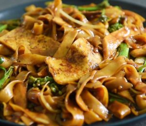 One of three vegan Chinese New Year recipes, this chow-fun style noodle dish contains tofu, broccolini, mushrooms, and bean sprouts