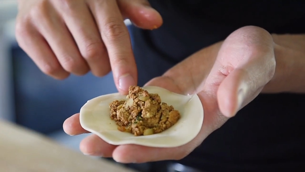 Yeung holds a dumpling wrapper filled with tofu crumble, showcasing one of his vegan Chinese New Year recipes