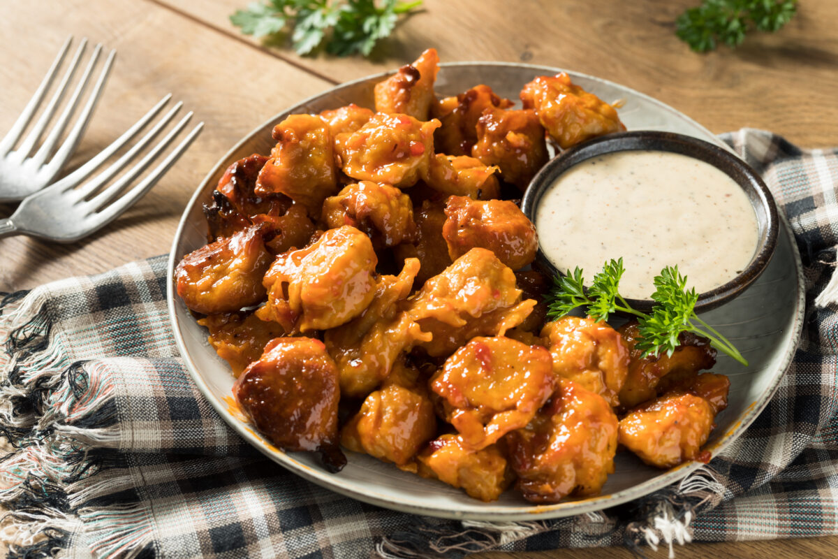 Photo shows a dish of vegan, plant-based Buffalo chicken wings with a ranch-style dip