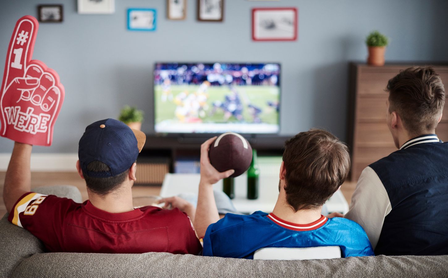 Photo shows three men on a sofa facing away from the camera and watching American football. According to a new survey, many Americans will be eating chicken wings during this Sunday's Super Bowl, and most of them would consider a plant-based or vegan alternative