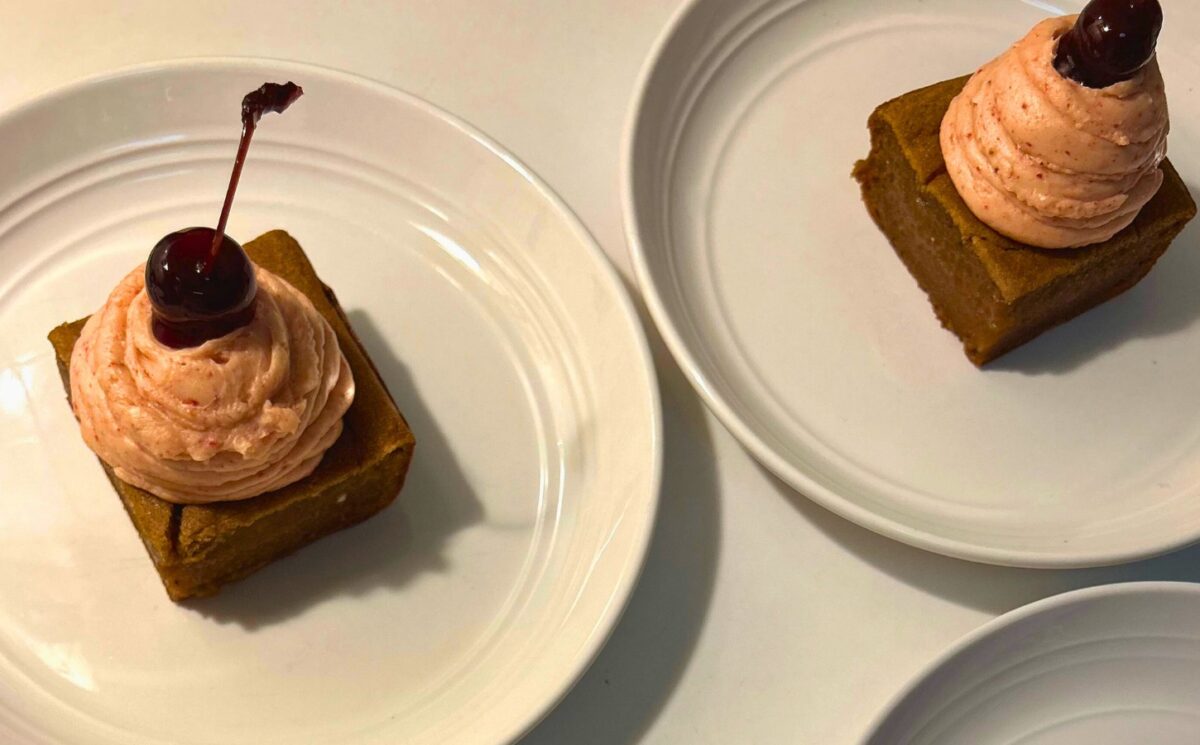 a photo of banana split butter mochi with strawberry buttercream and cherries