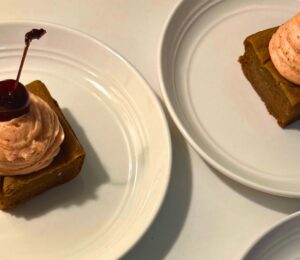 a photo of banana split butter mochi with strawberry buttercream and cherries