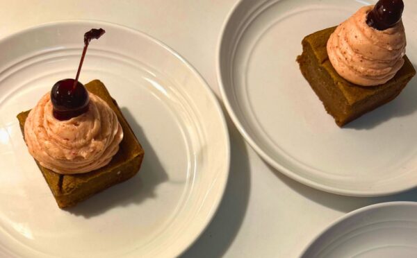 a photo of banana split butter mochi with strawberry buttercream and cherries