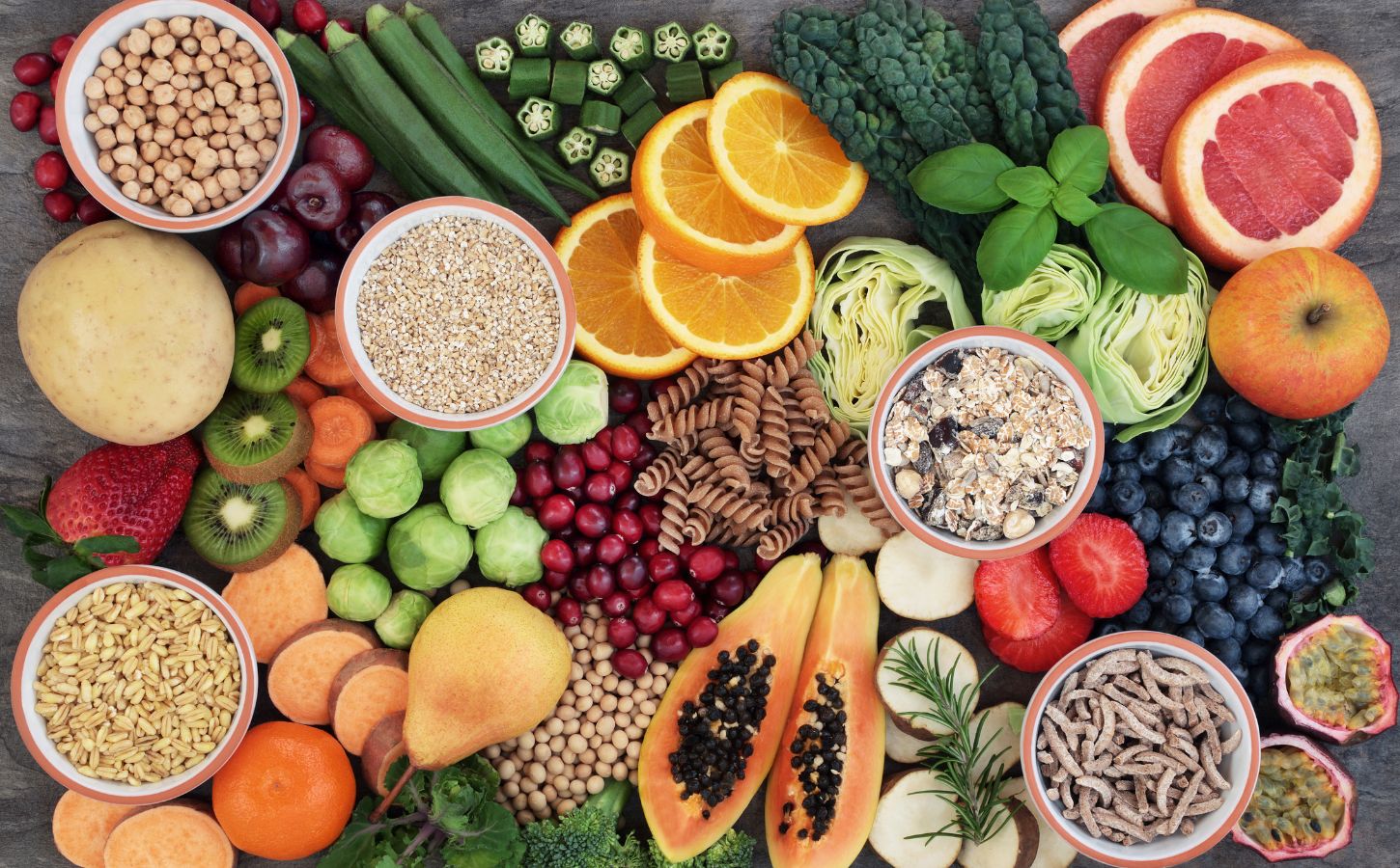 Photo shows a colorful mosaic of fresh fruit, vegetables, nuts, seeds, and other nutrient-dense plant-based foods. Hundreds of doctors and nutrition researchers have called for a return to evidence-based recommendations in the 2025–2030 Dietary Guidelines for Americans (DGA), including the prioritization of plant-based foods over high-impact meat and dairy